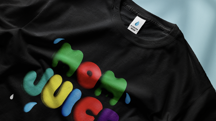 Mockup of a black t-shirt against a blue background, featuring the slogan 'Mom Juice' in multicoloured text with decorative water droplets